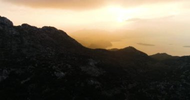 Gün doğumunda dağların üzerinde deniz ve güneş doğar. Yüksek kalite 4k görüntü