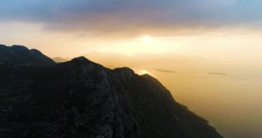 Gün doğumunda dağların üzerinde deniz ve güneş doğar. Yüksek kalite 4k görüntü