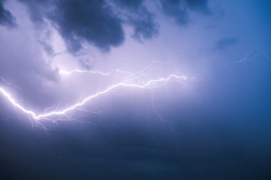 Lightning against the background of low cumulus clouds illuminates the environment.