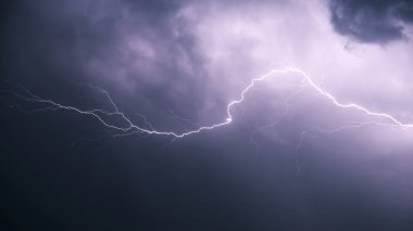 Lightning against the background of low cumulus clouds illuminates the environment.