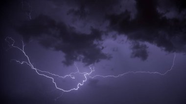 Lightning against the background of low cumulus clouds illuminates the environment.