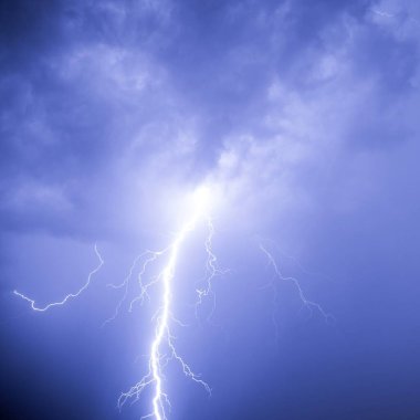 Lightning against the background of low cumulus clouds illuminates the environment.