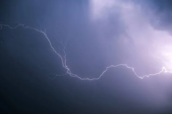 Lightning against the background of low cumulus clouds illuminates the environment.