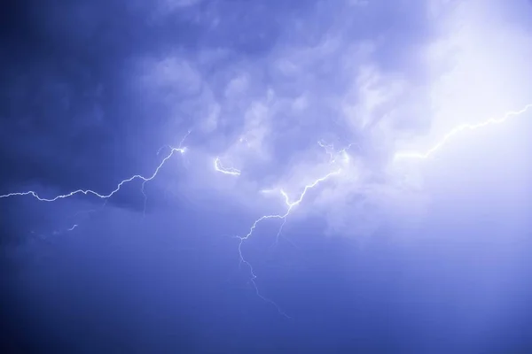 Lightning against the background of low cumulus clouds illuminates the environment.