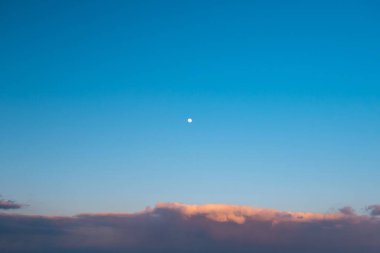Moon rise at sunset on blue sky