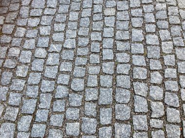 Grey Cobbled Roadway, Krakow, Poland, February 2022. Uneven with gravel in between.