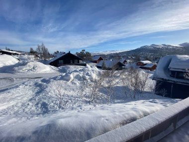 Snowy scenes in Hovden, Norway. Mountains and trees behind. Snow covered houses and blue skies. Bluebird weather. 