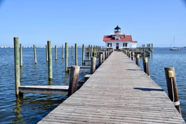 Arkası deniz manzaralı sahil yolu. Deniz feneri binası ve mavi gökyüzü. Manteo, NC, ABD. 1 Ekim 2019. 