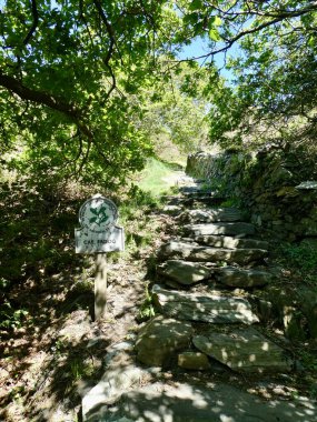 Taştan bir duvarın yanında Ulusal Güven işareti var. Barmouth, Galler, İngiltere. 4 Mayıs 2019. Cae Fadog, 