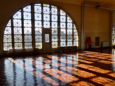 Ellis Adası Ulusal Müzesi 'nde bir iç mekan. Güneş, kemerli pencerelerden ahşap bir zemine parlıyor. New York, New York, ABD. 23 Aralık 2018. 