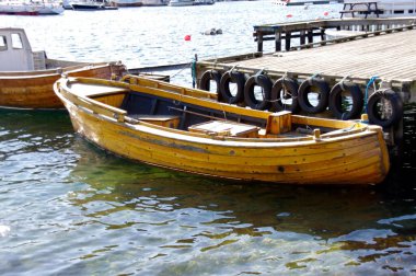 Tahta bir iskeleye demirlemiş bir kayık ve su üzerinde güneş parlıyor. Lillesand, Norveç. 8 Nisan 2013. 