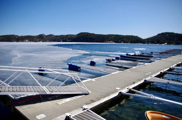 stock image Wooden jetty over frozen sea with mountains behind. Lillesand, Norway. April 8, 2013. 