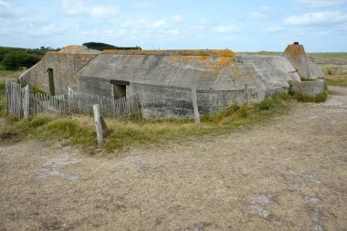 Utah sahilinin hemen dışında, mavi bulutlu gökyüzünün altında, 2. Dünya Savaşı 'ndan kalma Alman Beton Sığınağı. Utah Plajı, Fransa, 3 Temmuz 2023. 
