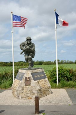 Monument to Major Richard D Winters and Easy Company, with US and French flags and countryside behind. Utah Beach, France, July 3, 2023.  clipart