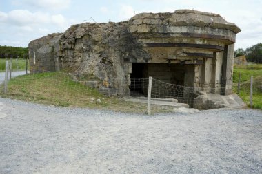 Çimenler ve çalılıklarla çevrili kraterlerin arasında Alman silah mevzilerinin kalıntıları. Pointe du Hoc, Fransa, 3 Temmuz 2023. 