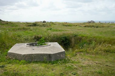 Çimenler ve çalılıklarla çevrili kraterlerin arasında Alman silah mevzilerinin kalıntıları. Pointe du Hoc, Fransa, 3 Temmuz 2023. 