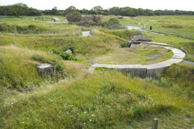 Çimenler ve çalılıklarla çevrili kraterlerin arasında Alman silah mevzilerinin kalıntıları. Pointe du Hoc, Fransa, 3 Temmuz 2023. 