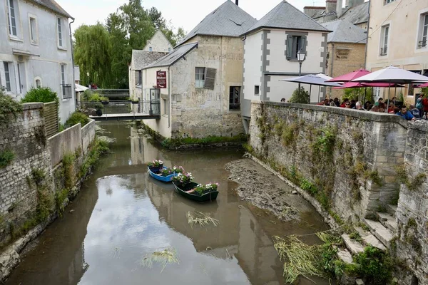 stock image Cafes and Bars overlooking the river, with 2 rowing boats containing flowers. Bayeux, France, July 5th, 2023. 