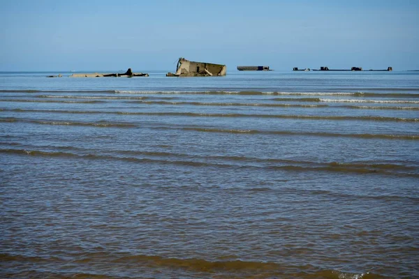 stock image Waves lapping on the beach with Remains of the WW2 D-Day Mulberry Harbour at Asnelles Beach. Arromanches, France, July 5, 2023. 