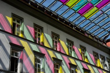 Aşağıdaki duvarda oynayan pencerelerden gelen sarı ve pembe ışık. Innsbruck, Avusturya 