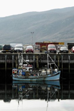 Balıkçı teknesi UL562 iskeleye demirlemiş ve suya yansımış. Ullapool, İskoçya, İngiltere, 18 Eylül 2014. 