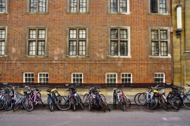 Arkasında kırmızı tuğla bina olan bir sıra bisiklet.. 