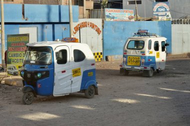 Tuktuk 'lar arkada binalarla caddeye park etmiş. Puno, Peru, 8 Ekim 2023. 