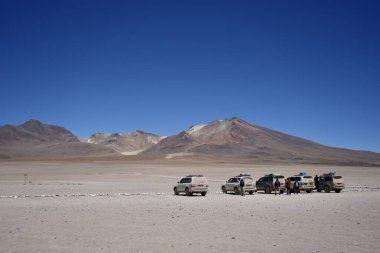 Çölde, mavi gökyüzünün altında dağlar olan 4x4 araçlar. Potosi, Bolivya, 13 Ekim 2023. 