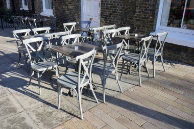 Londra Caddesi 'nde gri kafe sandalyeleri, arkasında beyaz kapılı kırmızı tuğlalı evler..
