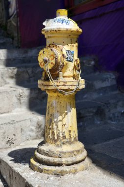 Kırsal sarı yangın musluğu güneş ışığında, arkasında adımlar var. Valparaso, Şili, 17 Ekim 2023. 