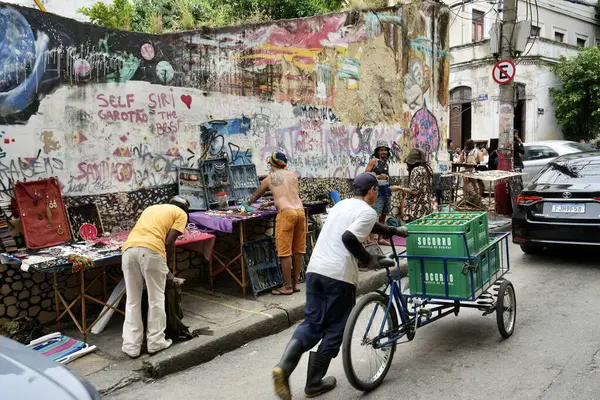 stock image Street sellers in Lapa close to the Selaron Steps, with colourful street art behind. Rio de Janeiro, Brazil, October 27, 2023. 