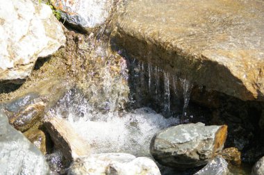 Güneş ışığında kayaların üzerinden akan temiz su. 