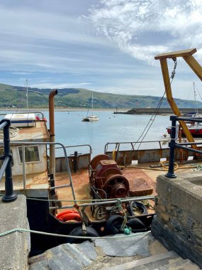 Barmouth 'un karşısındaki sahil manzarası limandaki paslı bir balıkçı teknesinin üzerinde. Barmouth, Galler, İngiltere. 11 Mayıs 2024. 