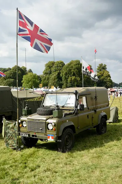 stock image A British Army Land Rover Defender under a Union Jack at a country fair, Derbyshire, UK, August 30, 2024. 