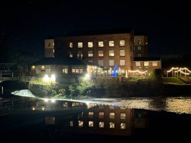 Darleys Restaurant reflected in the river Derwent next to the footbridge and weir. Darley Abbey, Derby, UK. November 22, 2024.  clipart