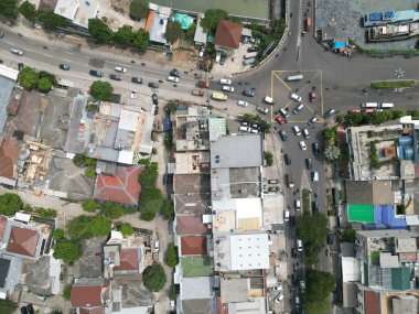 Jakarta şehrinin atmosferi yukarıdan nehir ve sokak faaliyetlerinin görüntüsüyle görülmektedir.