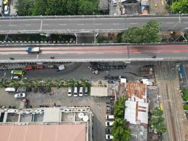 Jakarta şehrinin atmosferi yukarıdan nehir ve sokak faaliyetlerinin görüntüsüyle görülmektedir.