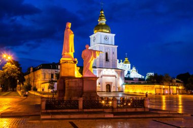 Aziz Michaels Altın Kubbe Manastırı, Kiev Ukrayna. Yüksek kaliteli fotoğraf, mavi saat alacakaranlıklarında dramatik bulutlu bir gökyüzü ve manastırın önündeki meydanın önündeki fenerlerden gelen altın bir ışık.