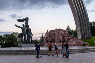 Bir grup insan, Kiev 'deki Ukrayna Özgürlük Kemeri' nin altında Sovyet Dostluk Nişanı 'nı elinde tutan Rus ve Ukraynalı bir işçiyi resmeden bir heykelden içeri giriyorlar..