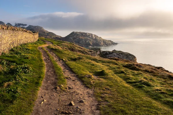 Howth Island, Dublin, İrlanda 'da yürüyüş parkurunda. Denizin üstünde mavi bir gökyüzünün altında sis var. Güneşin altın ışınları sahneyi aydınlatıyor. Yumuşak ışık. Yüksek kalite fotoğraf