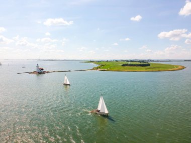 Hollanda 'daki bir gölde, tipik bir Hollanda mavisi gökyüzü altında yelkenlilerin insansız hava aracı görüntüleri. Yüksek kalite fotoğraf