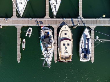 A top-down view of a marina in Zeeland, The Netherlands. A few sailing boats, a SUP and a dinghy moored at the jetty. High quality photo