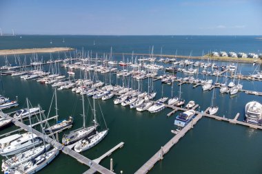 A drone view of a marina in Zeeland, The Netherlands. Roompot Marina.Holiday homes dot the shore under blue skies. High quality photo