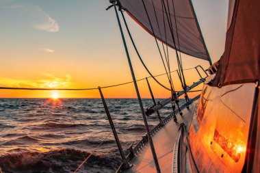 Dramatic orange sunset at sea seen from a sailboat. Reflections on the boats windows and in the waves.Taken at the North sea, The Netherlands. High quality photo