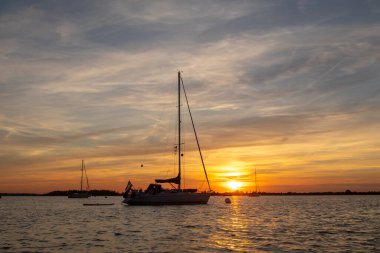 Sailing boat anchored with dramatic sunset. Orange skies with cirrus clouds.High quality photo
