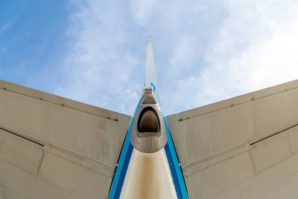 Looking up to the tail and stabiliser of a blue aircraft. The Auxiliary Power Unit, APU, is visible as well as the horizontal end vertical stabiliser. Blue sky. High quality photo