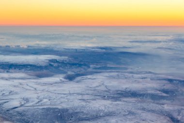 Aerial view of the Peak District, during sunset in winter with snow. Pink and orange skies with snow on the tops of the mountains and hills of the Peak District National Park, England, UK, Europe