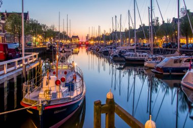 Hollanda, Harlingen 'deki Noorderhaven, kuzey limanı manzarası. Tarihi KNRM kurtarma botu ön cephede ve tarihi evlerin önünde demirli yatlar. Yüksek kalite fotoğraf
