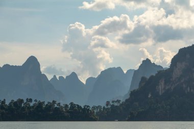 Khao Sok Ulusal Parkı, Tayland 'daki yeşil ormanlarla kaplı kireçtaşı uçurumları. Mavi göl ve uzun kuyruk teknesi, mavi gökyüzü. Yüksek kalite fotoğraf