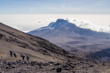 Kilimanjaro Dağı 'nın yamacında yürüyüş yapan yürüyüşçüler. Üstü karla kaplı, gün doğumunda dramatik bir ruh hali. Tanzanya, Afrika. Yüksek kalite fotoğraf